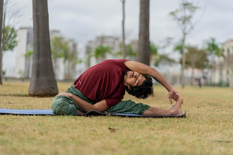 a man sitting in the grass with his hands on his knees