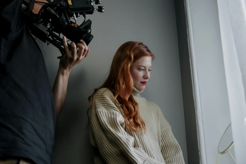 a man taking pictures of a red headed woman