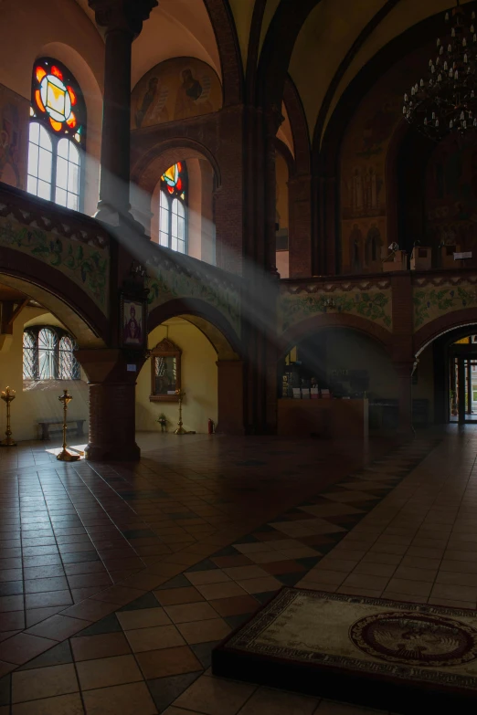 a large hall is adorned with three stained glass windows