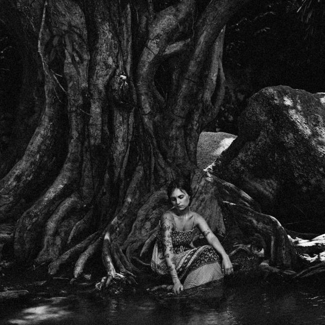 a man in the water sitting next to a tree