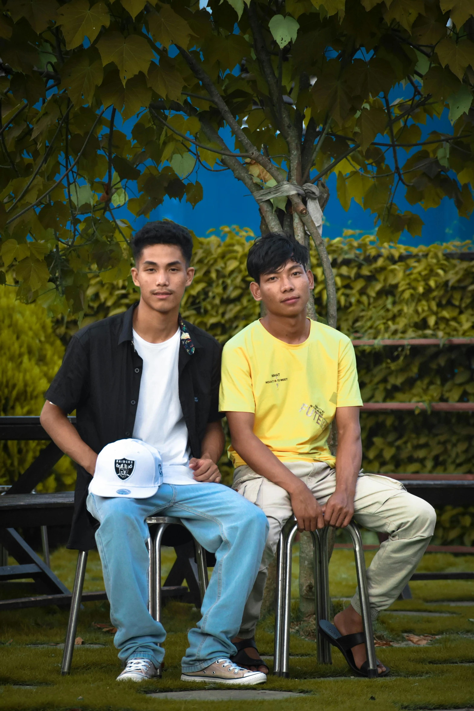 two young men sitting next to each other on metal folding chairs