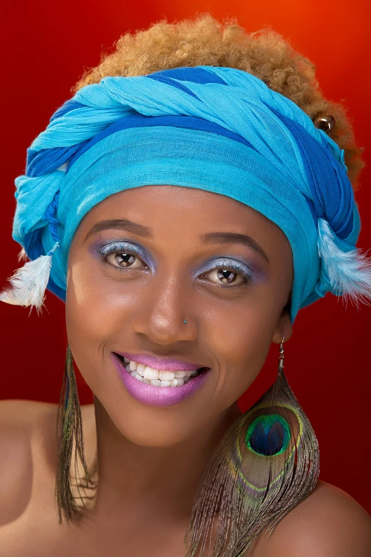 a woman in blue head wrap with feather earrings