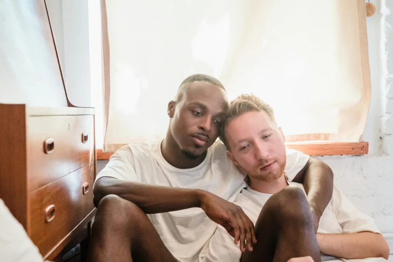 two men are sitting next to each other on the bed