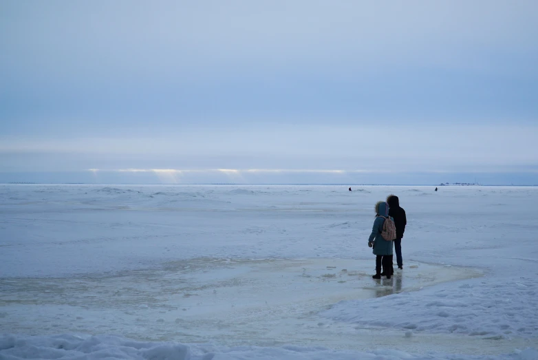 two people standing in an open area by the water