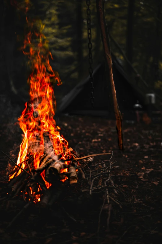 a camp fire with a tent in the background