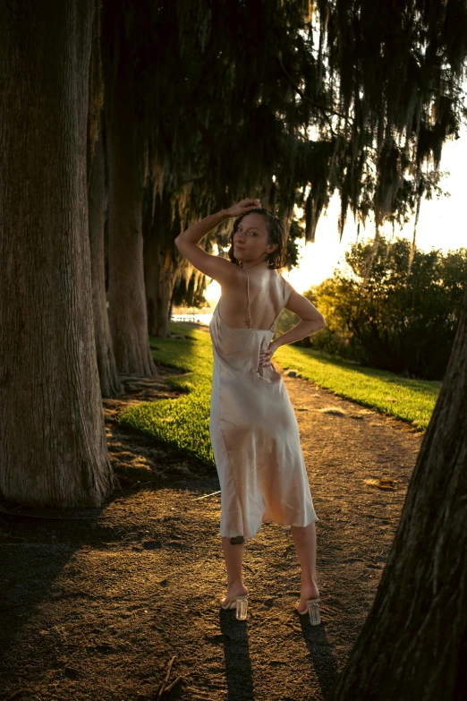 a woman poses underneath a tree in a white dress