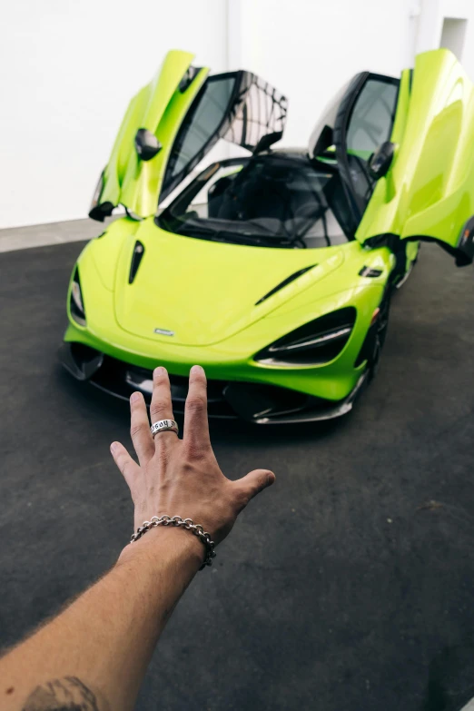 a man is reaching up to a bright colored sports car