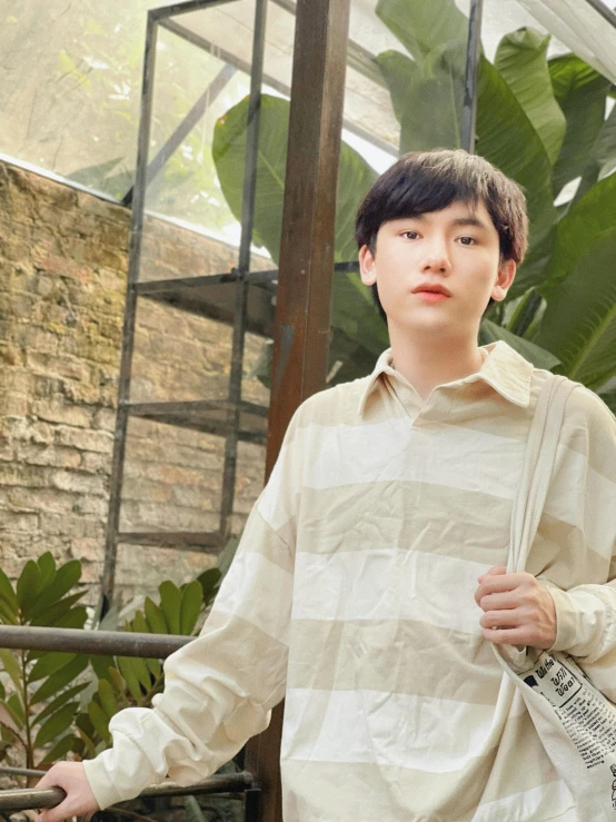 young man holding a purse near a tree