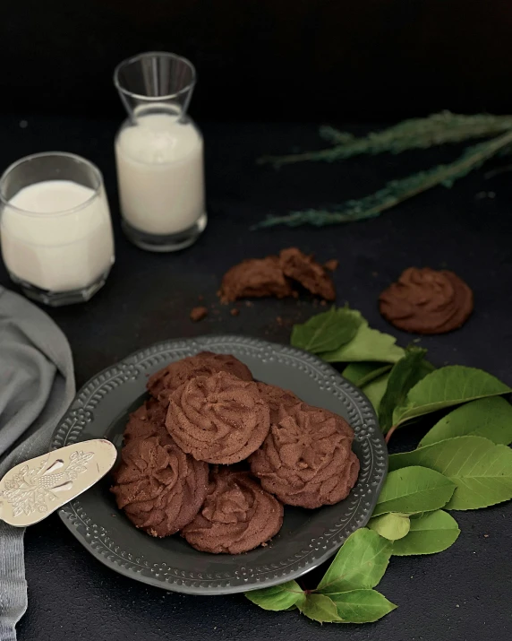 chocolate cookies sitting on a plate with two glasses of milk