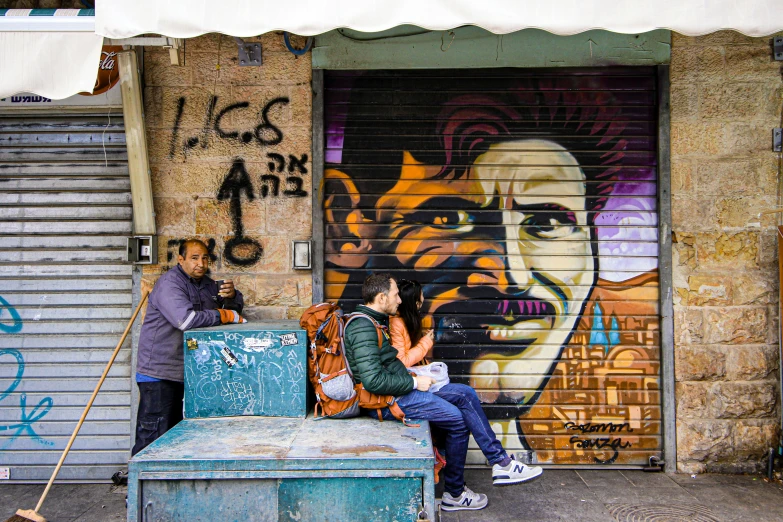 two people sit on an old, dirty bench with graffiti in the background