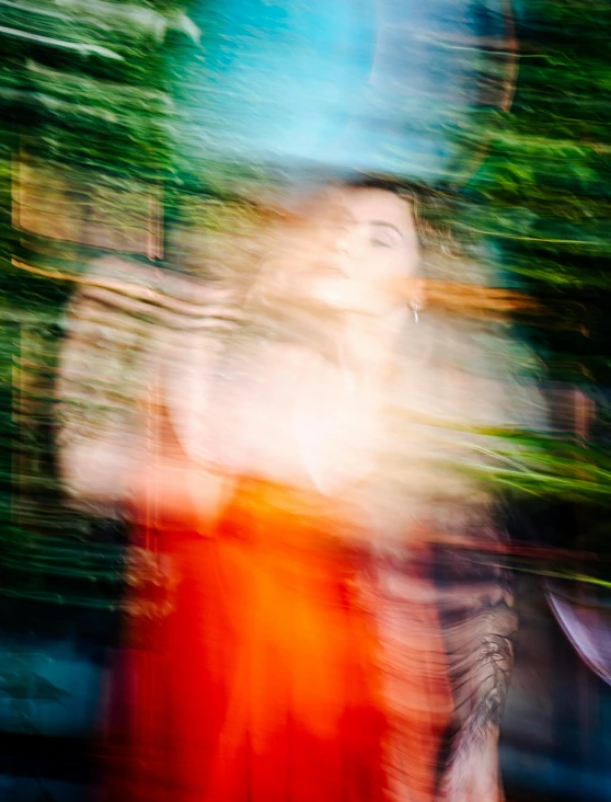 blurry image of a woman in red dress and trees