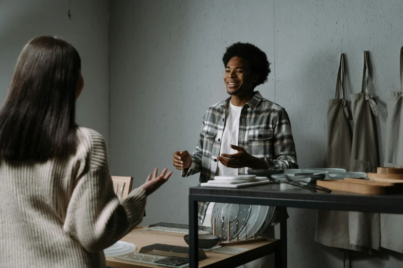 a young man is having a discussion with an older woman in her studio