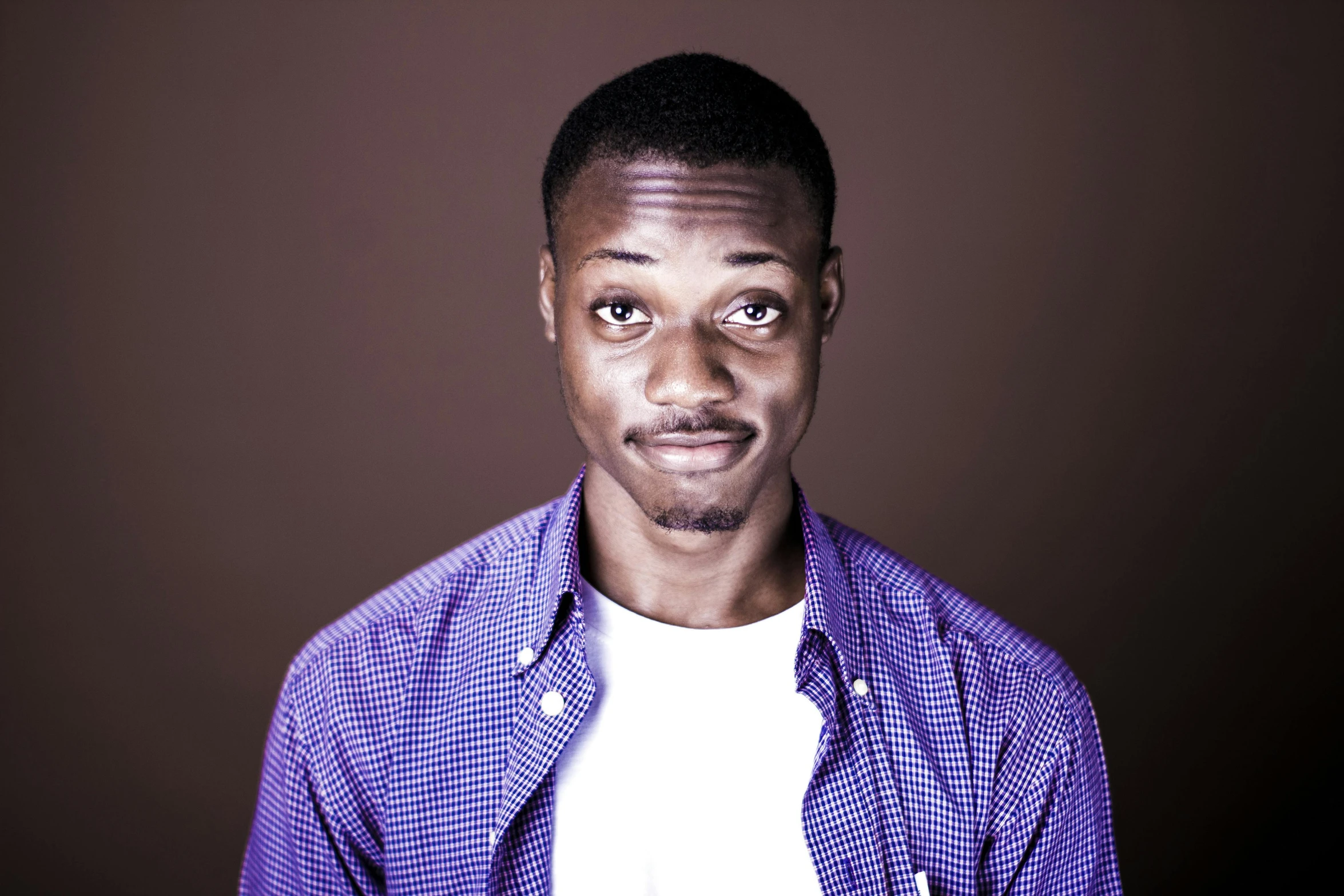 a black man in a purple shirt and white t - shirt