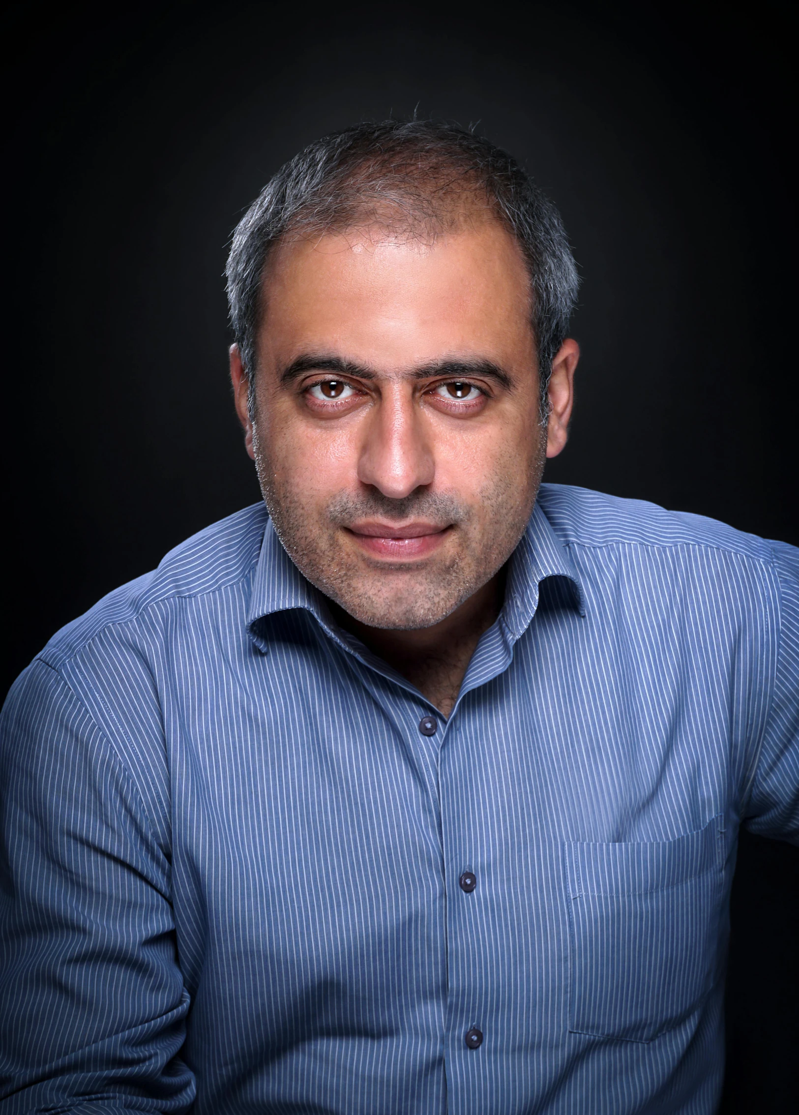 an older man wearing a blue shirt and posing for a portrait