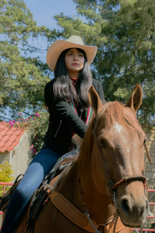 a woman wearing a hat and a cowboy outfit on a horse