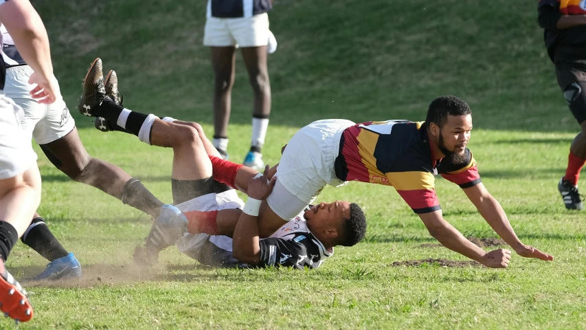 a man lays on the ground as he runs over another player to kick a ball