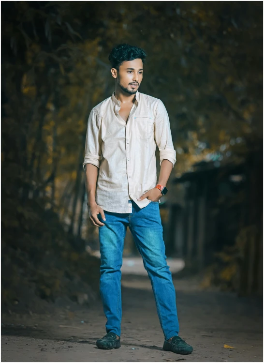 a man standing on a road wearing blue jeans and shirt