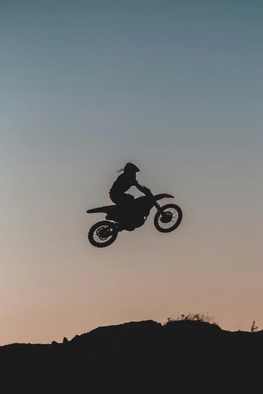 man jumping over hill with bike in air
