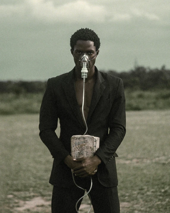 man wearing a mask holding a speaker with wires attached to his head