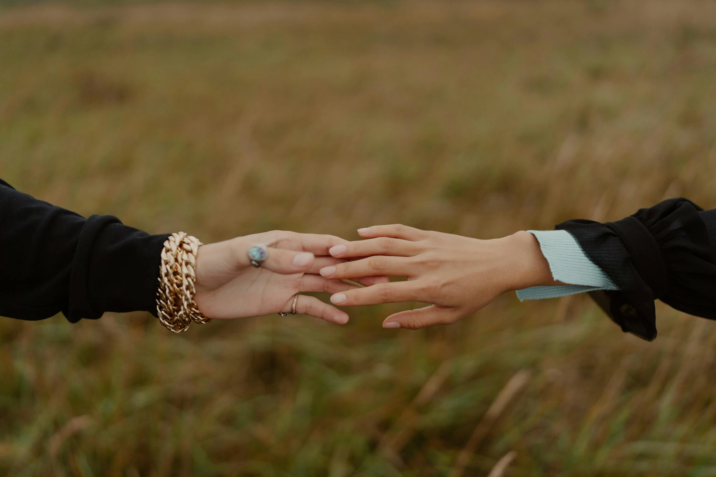 two people holding hands in front of some grass