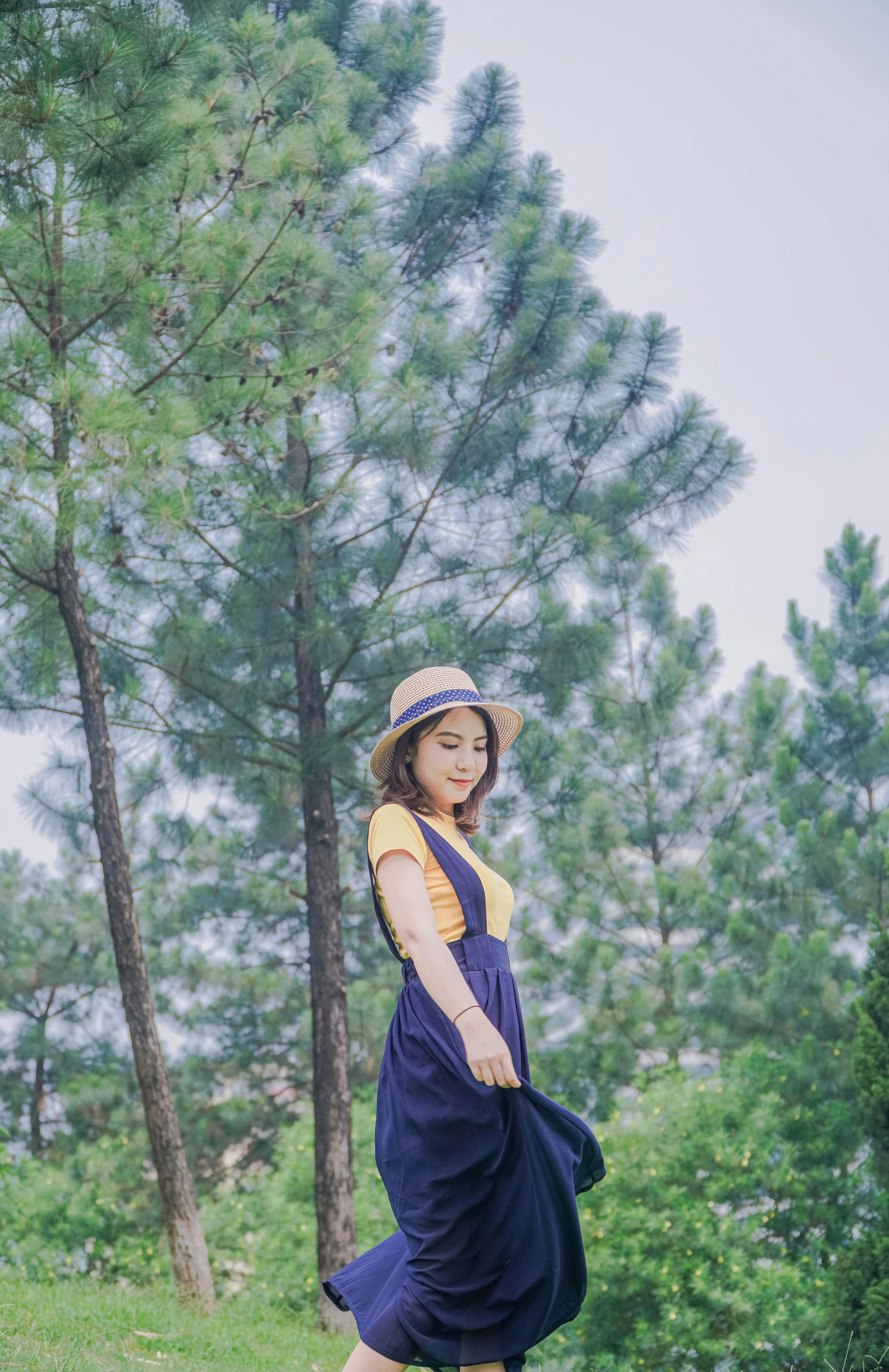 a young woman standing in the grass next to trees