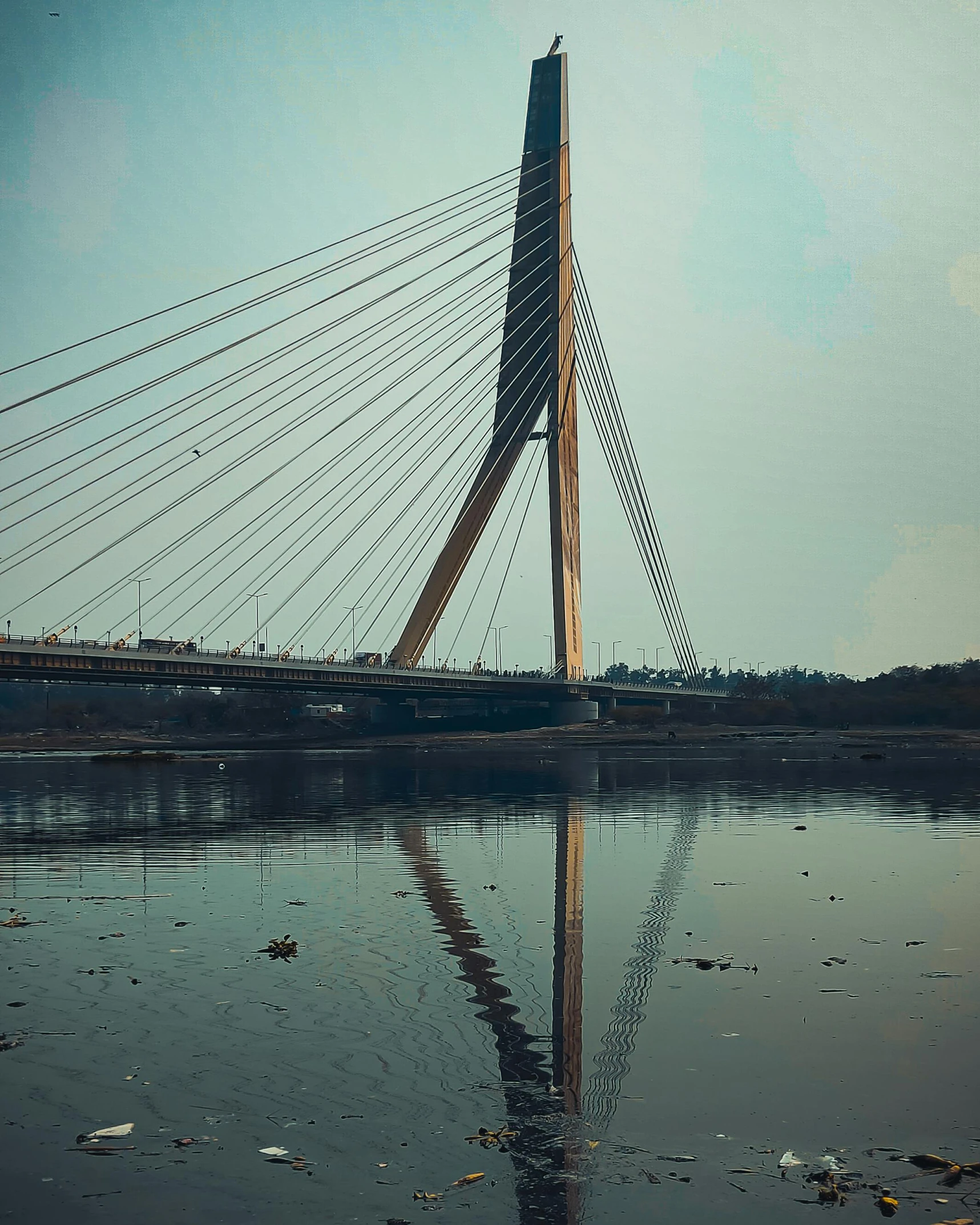 a very tall bridge over some water on a sunny day