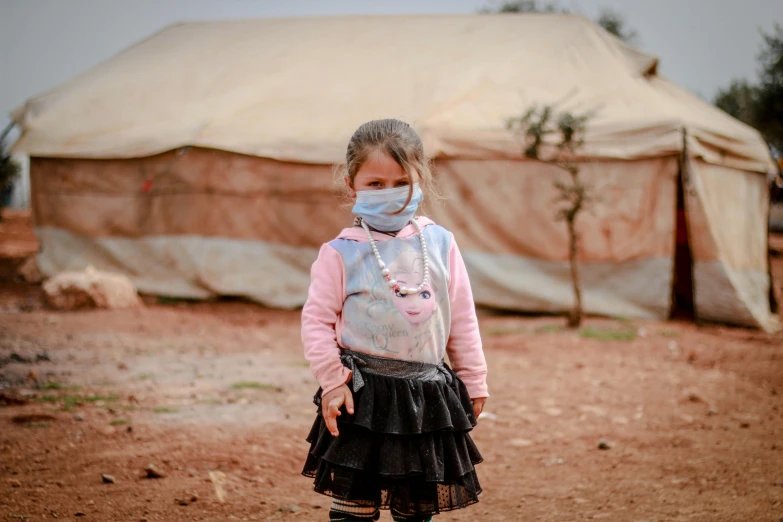 a girl in a face mask standing by a tent