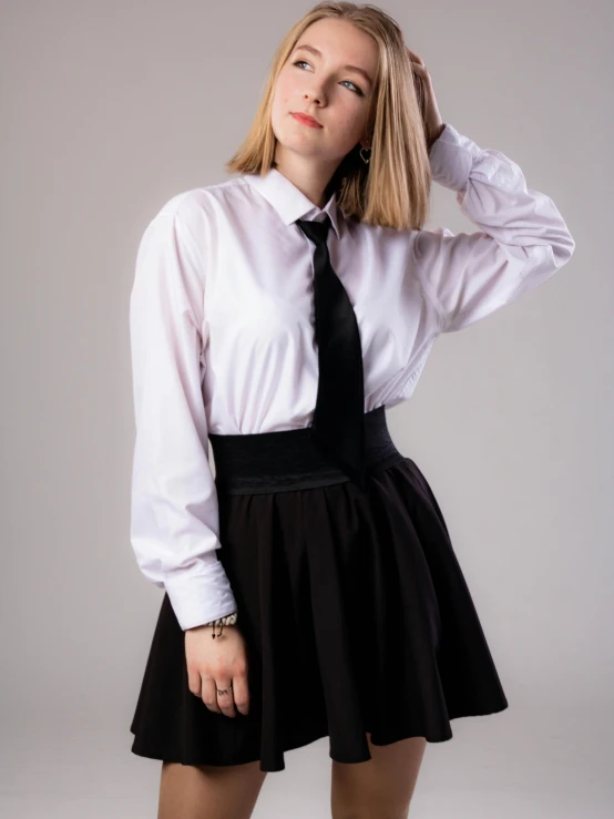 a  in a white shirt and black skirt is posing