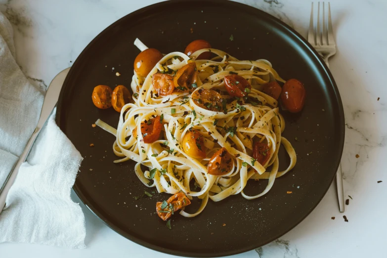 pasta with tomatoes, shrimp, and parmesan cheese served on a black plate