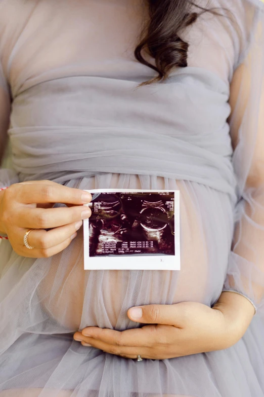 a woman in a dress holds up a small card with a picture