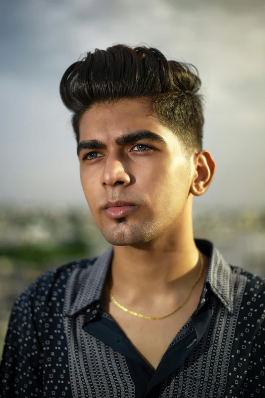 a young man wearing a necklace stares away from the camera