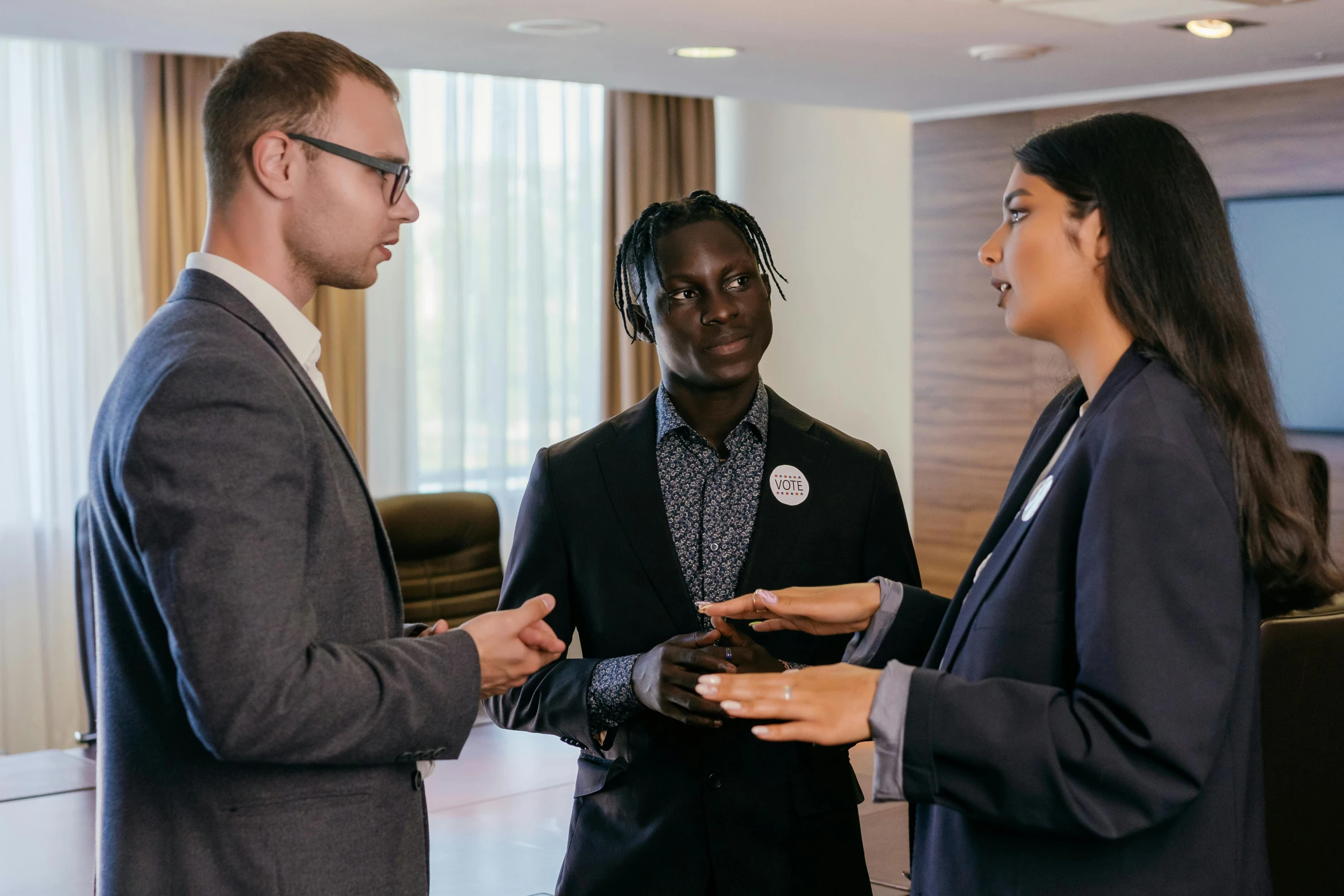 three people in business attire talk to each other