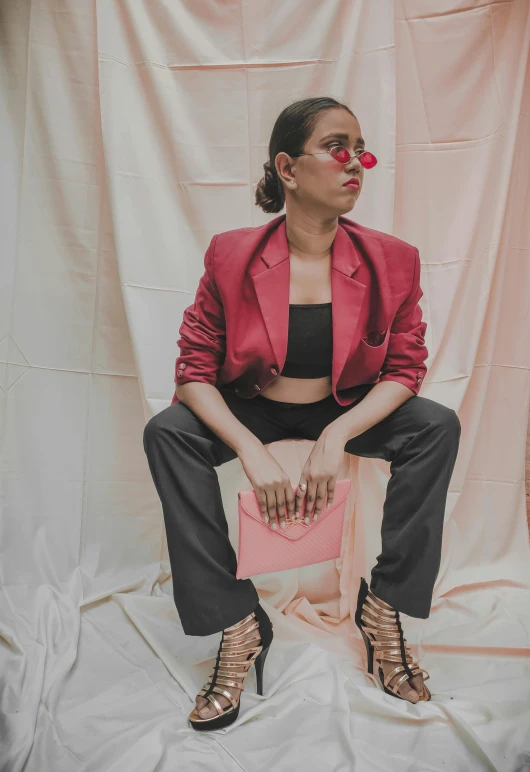 a woman poses with a clutch bag and pink flower in her mouth