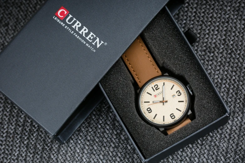 a brown watch sitting in a box on top of a blanket