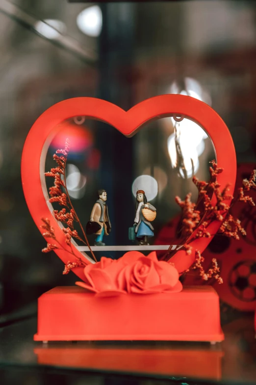 a heart shaped display with two little statues inside it