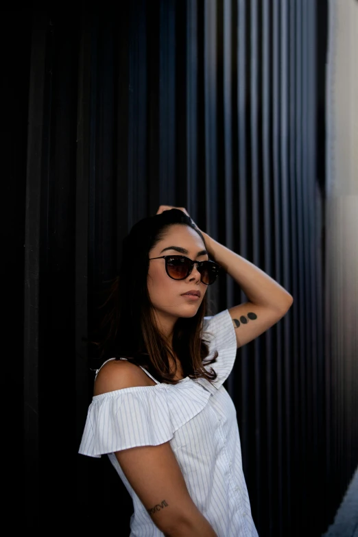 a woman in sunglasses standing outside of a wall