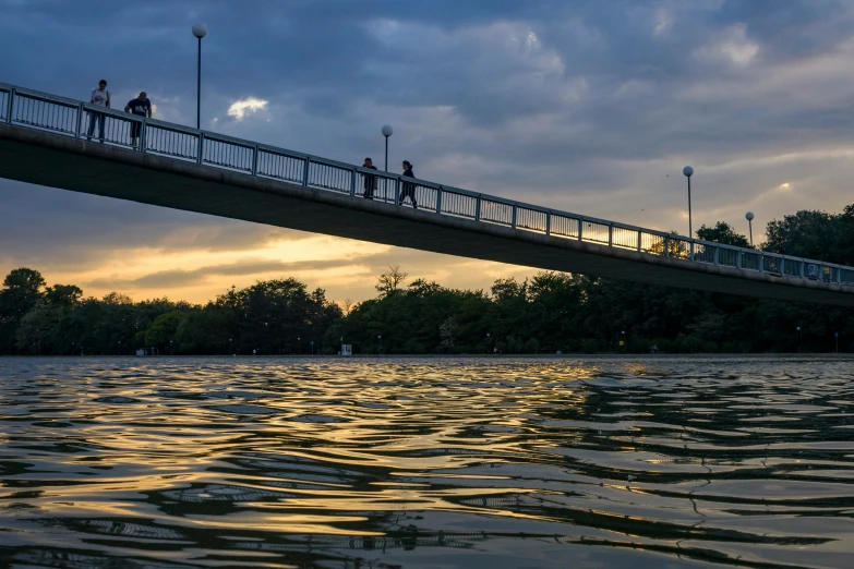 a view of people walking along a pier on a river