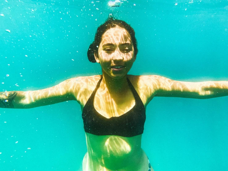 a woman in a black bikini under water