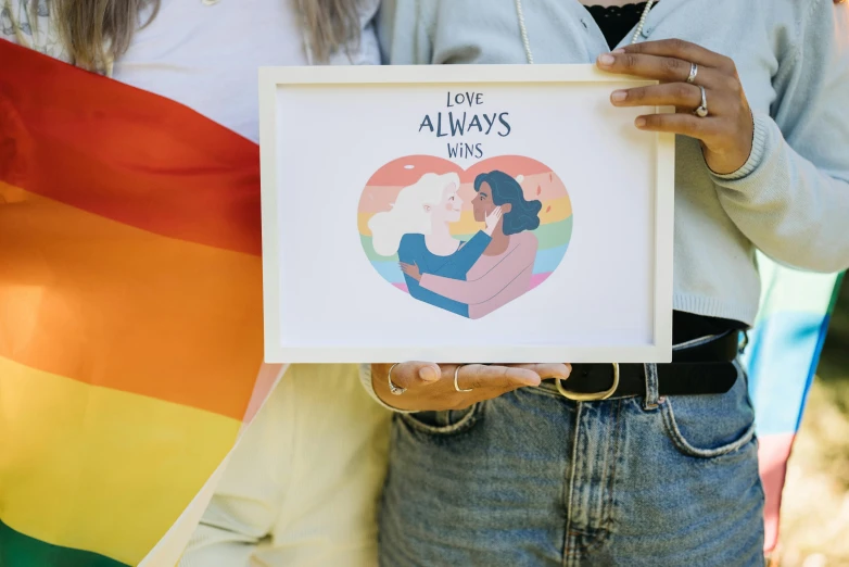 couple holding po on rainbow flag in front of other