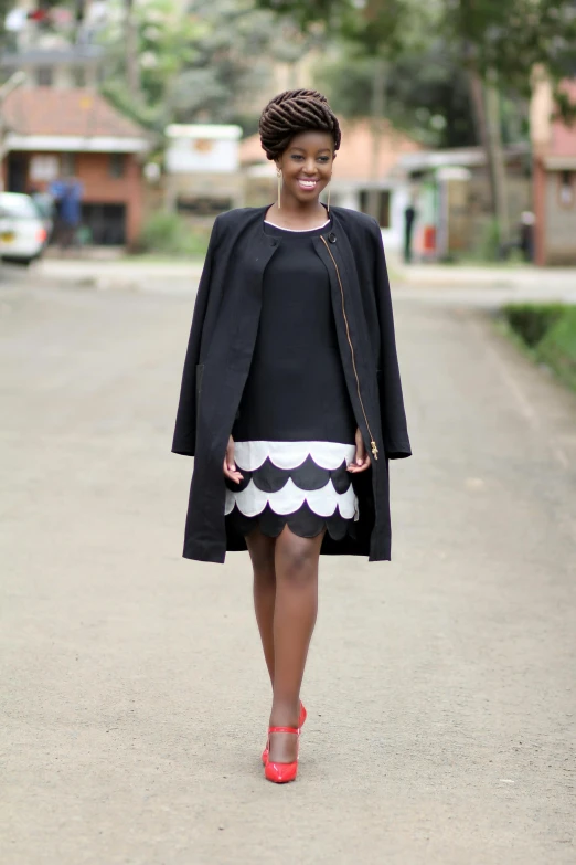 a woman in black and white dress walking down a street