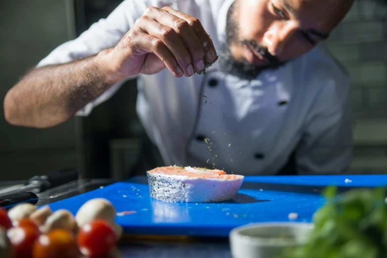 chef sprinkling seasoning onto a sushi