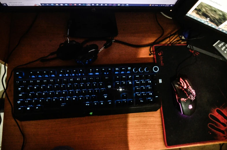 computer keyboard and mouse on wooden table with multiple electronics