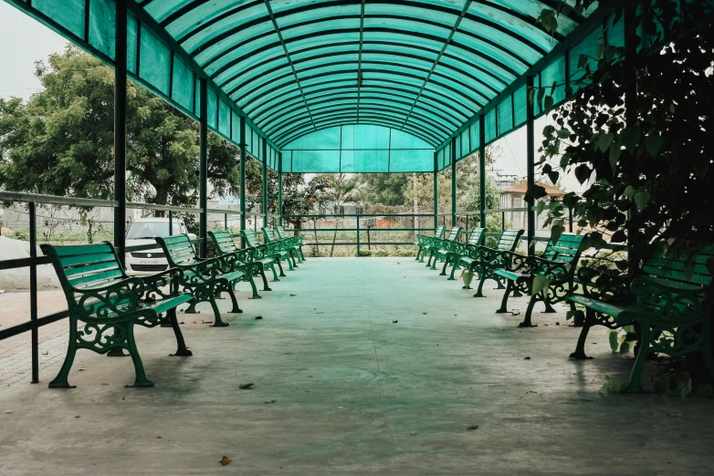 green benches lining a pathway under a blue roof