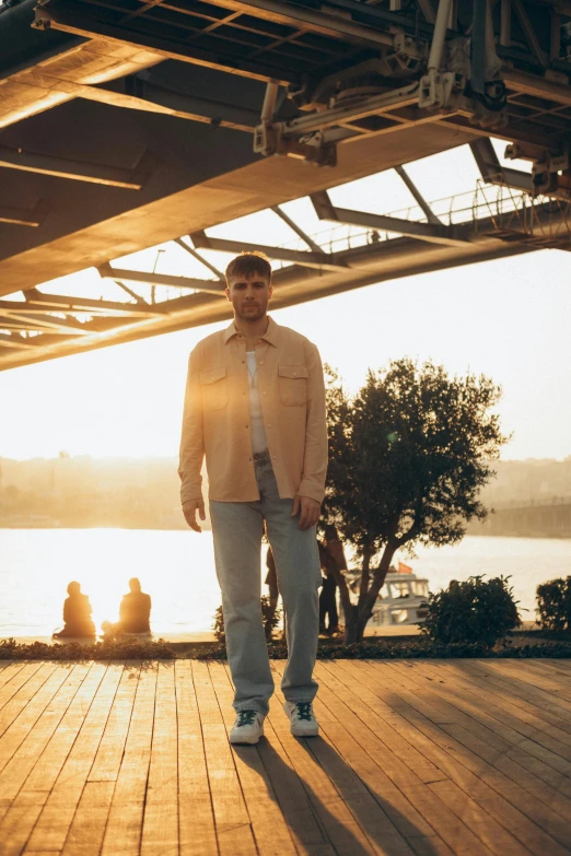 a man in a beige shirt and jeans standing on the deck