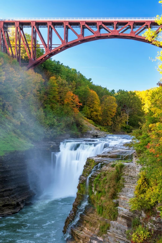 a bridge is spanning a river below a waterfall