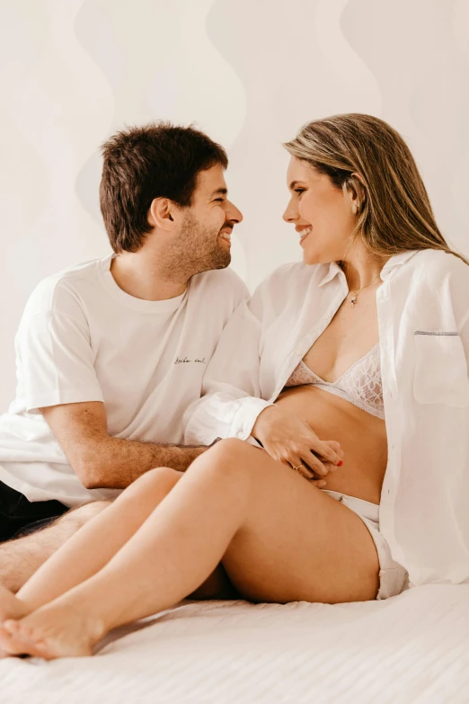 a man sitting next to a woman on top of a bed