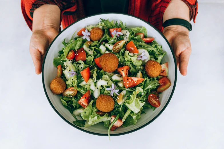 person's hands holding large bowl of food on table