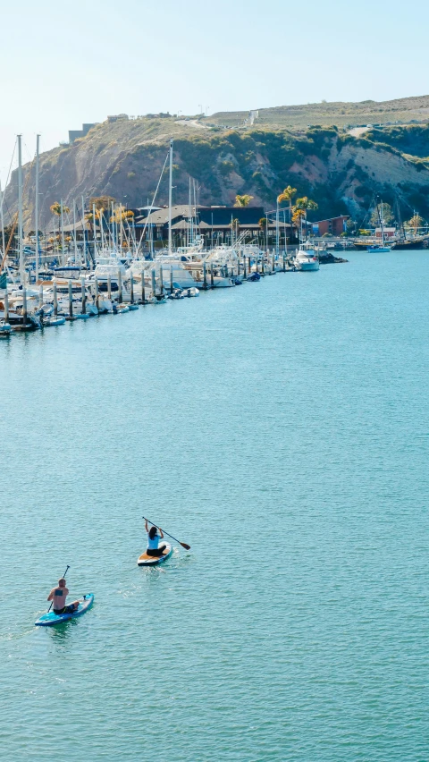 three people paddle their surfboards in the water in front of the marina