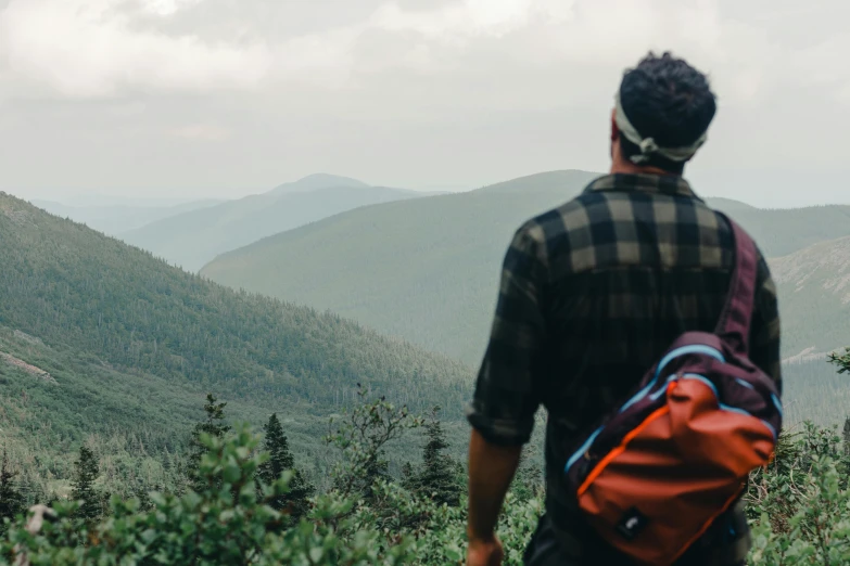 the back of a person with a backpack overlooking a mountain range