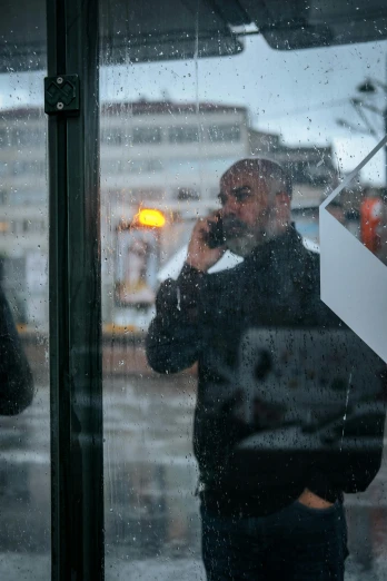 man on cellphone in rain soaked city area